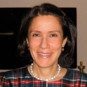 Mulher branca decabelos escuros. Usa um colar e está sorrindo Mulher branca decabelos escuros. Usa um colar e está sorrindo