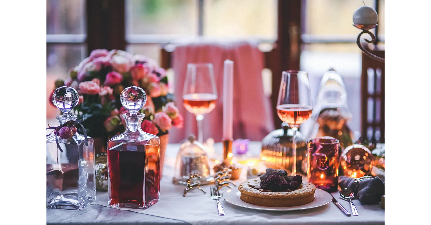 Elegant candlelit dinner table with flowers, desserts and wine, perfect for a romance-themed book club gathering.