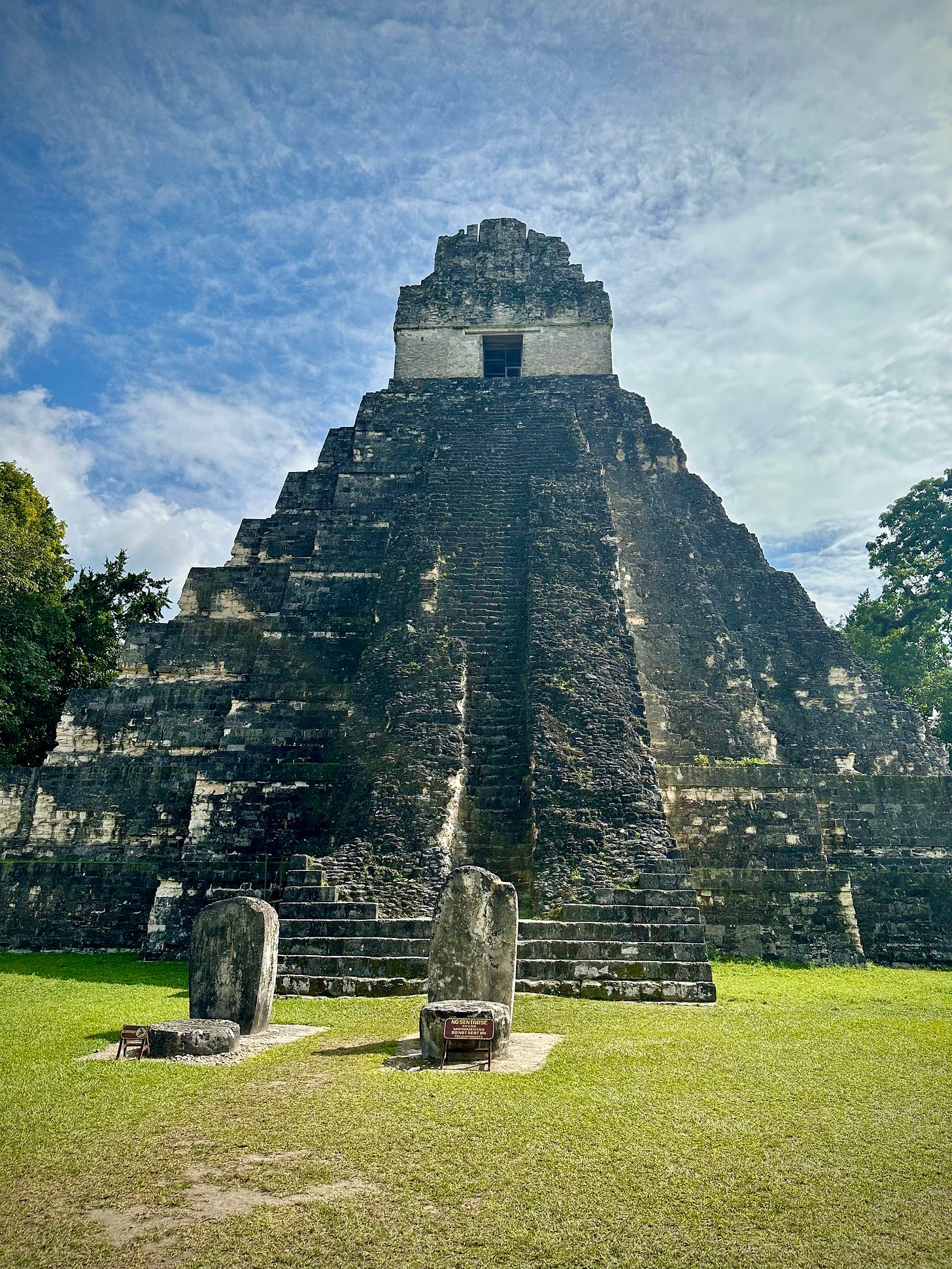 A Mayan temple towers over green jungle landscape and blue skies.