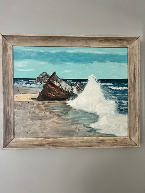 A series of mixed-media cards hang on a beaded string and in a frame, a painting of a shipwreck ocean scene with a wooden frame, an abstract view through my dining room window of the mountain carved into a wooden cutting board, and a patchwork quilt laying atop a couch.