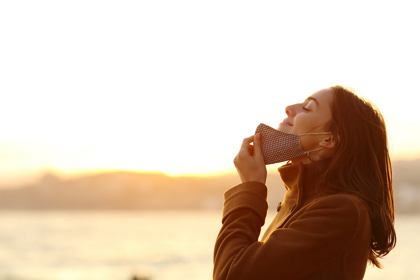 Woman pulling down mask and smiling at the fresh air
