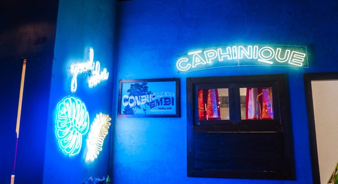 A blue wall with neon signs on it and wall art
