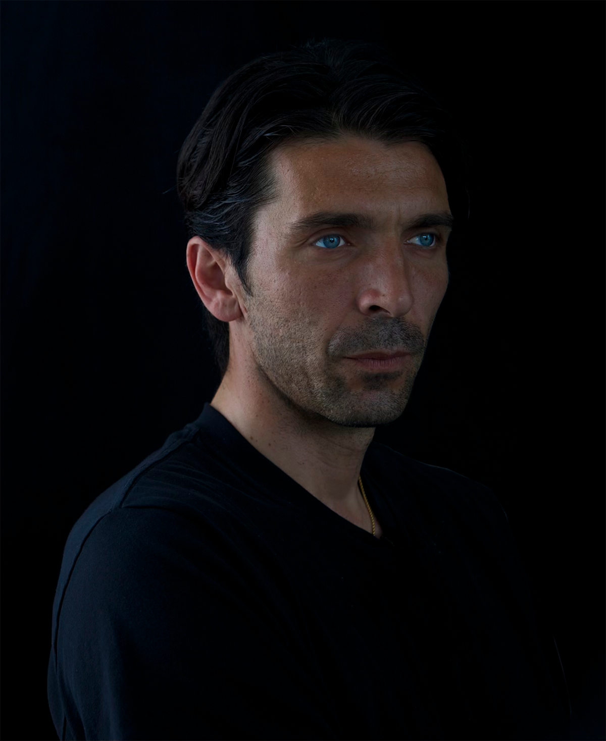 Portrait of Gianluigi Buffon with piercing blue eyes against a black background.