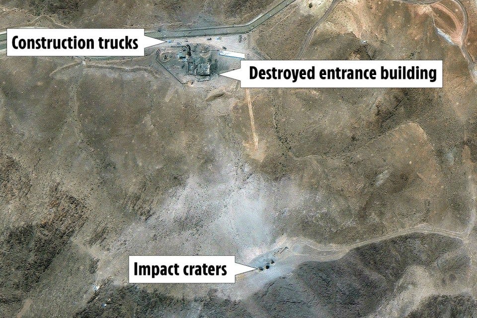 Aerial view of impact craters, a destroyed entrance building, and construction trucks.