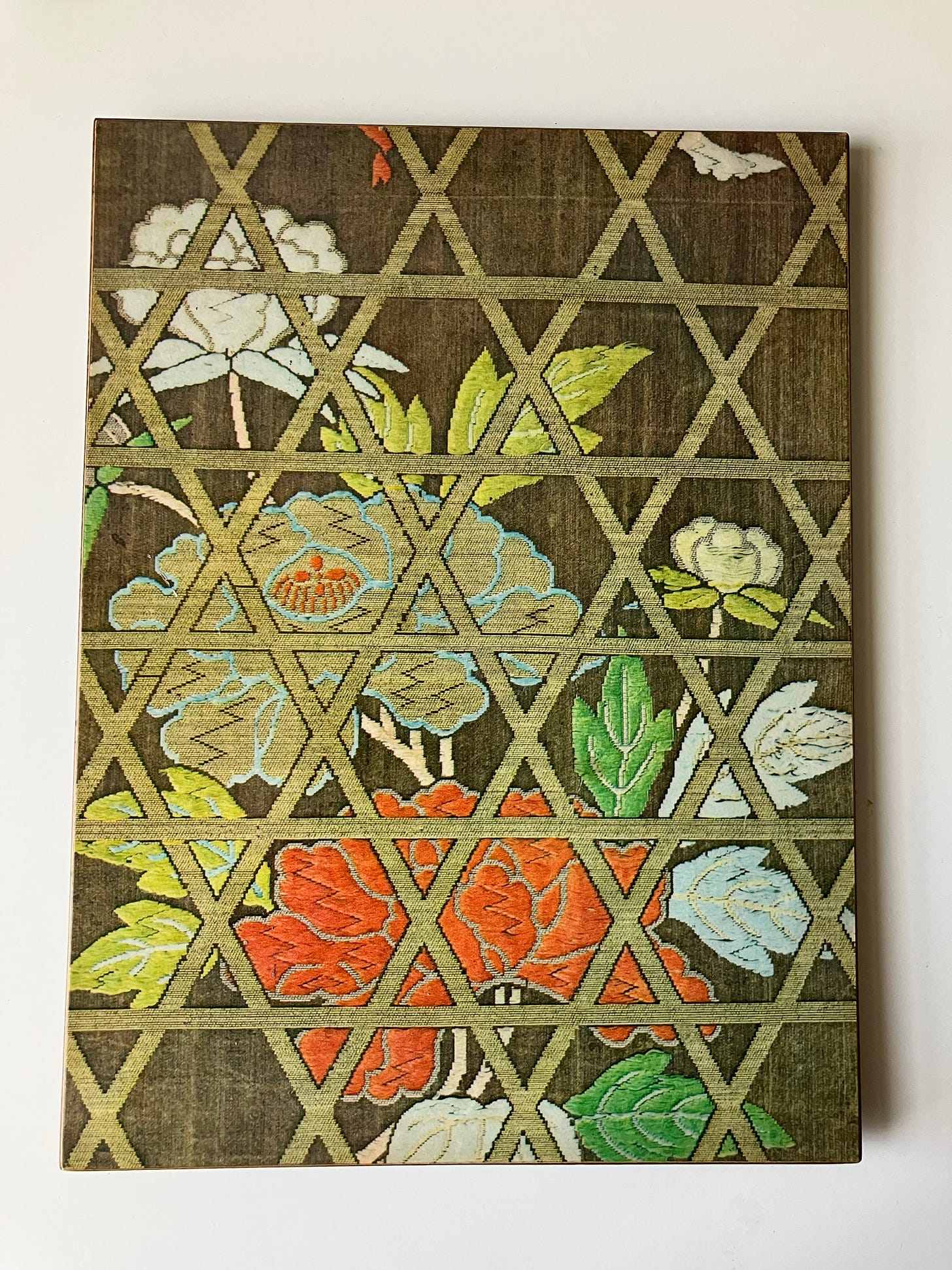 image of white, tan, and orange flowers behind triangular grid of trellis