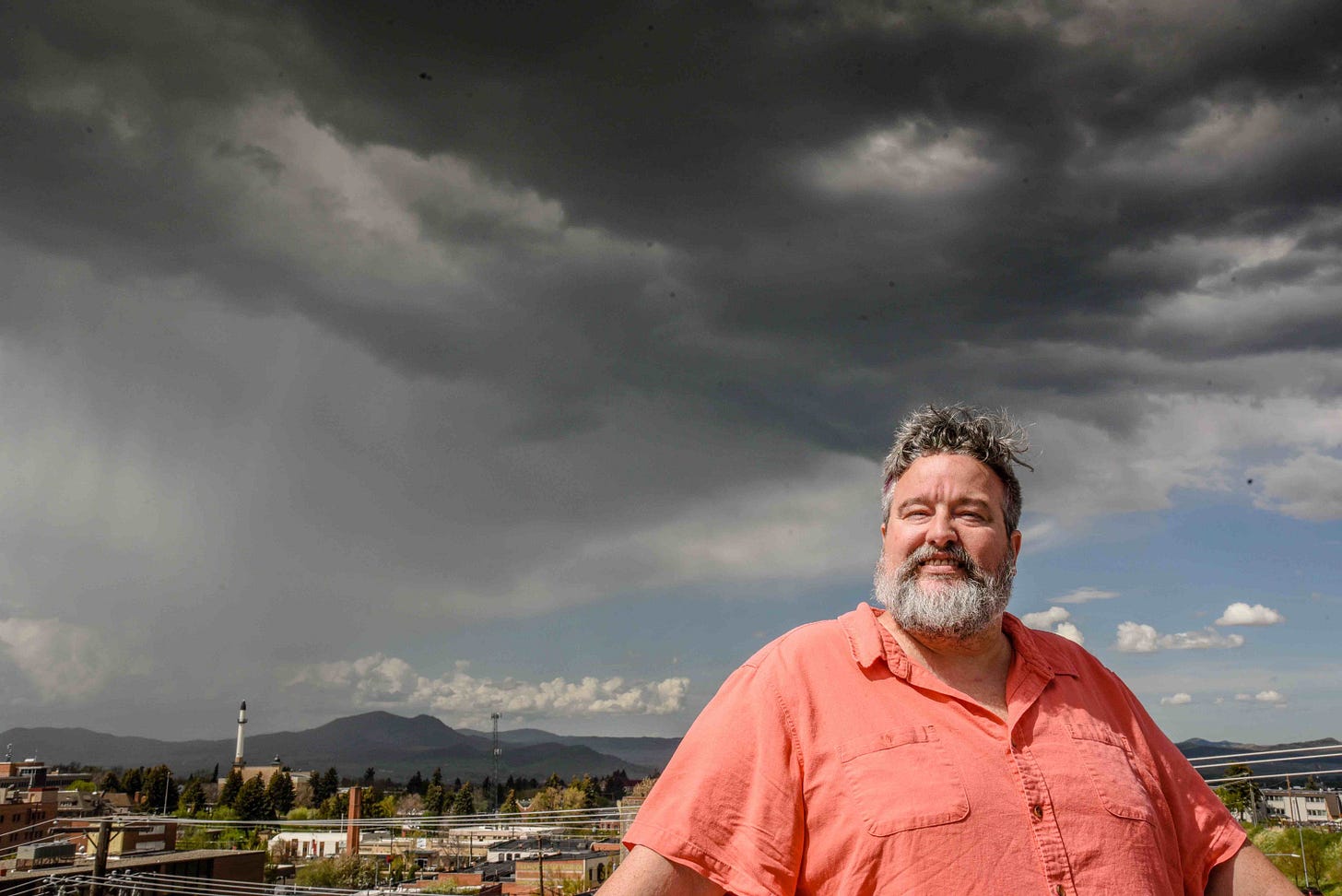 man in orange shirt under dramatic skies