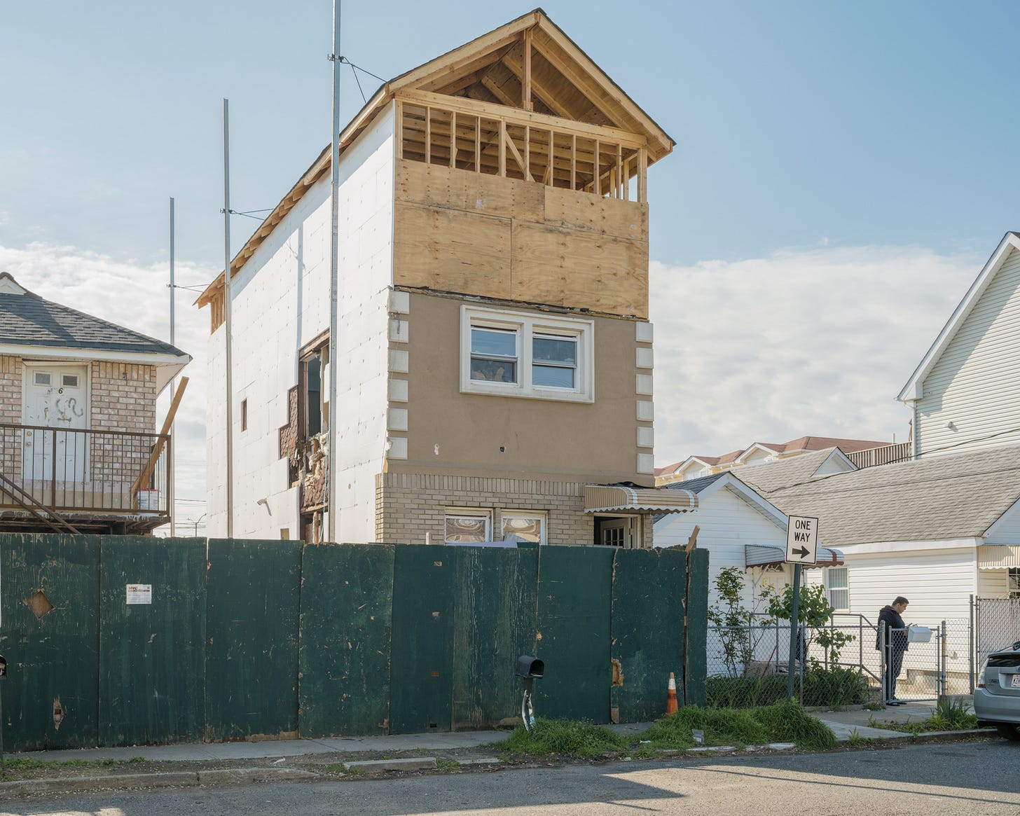 silouhette-of-man-checking-his-mail-next to-tall-house-under-construction-
