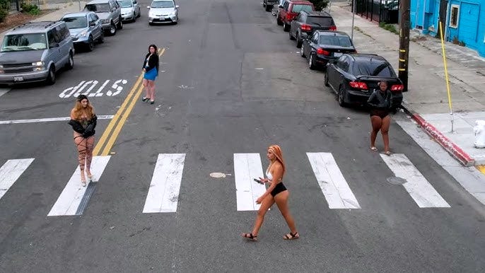 Women crossing the street on International Boulevard. Oakland, California. (Image source: Street Clipz / YouTube) Women crossing the street on International Boulevard. Oakland, California. (Image source: Street Clipz / YouTube)