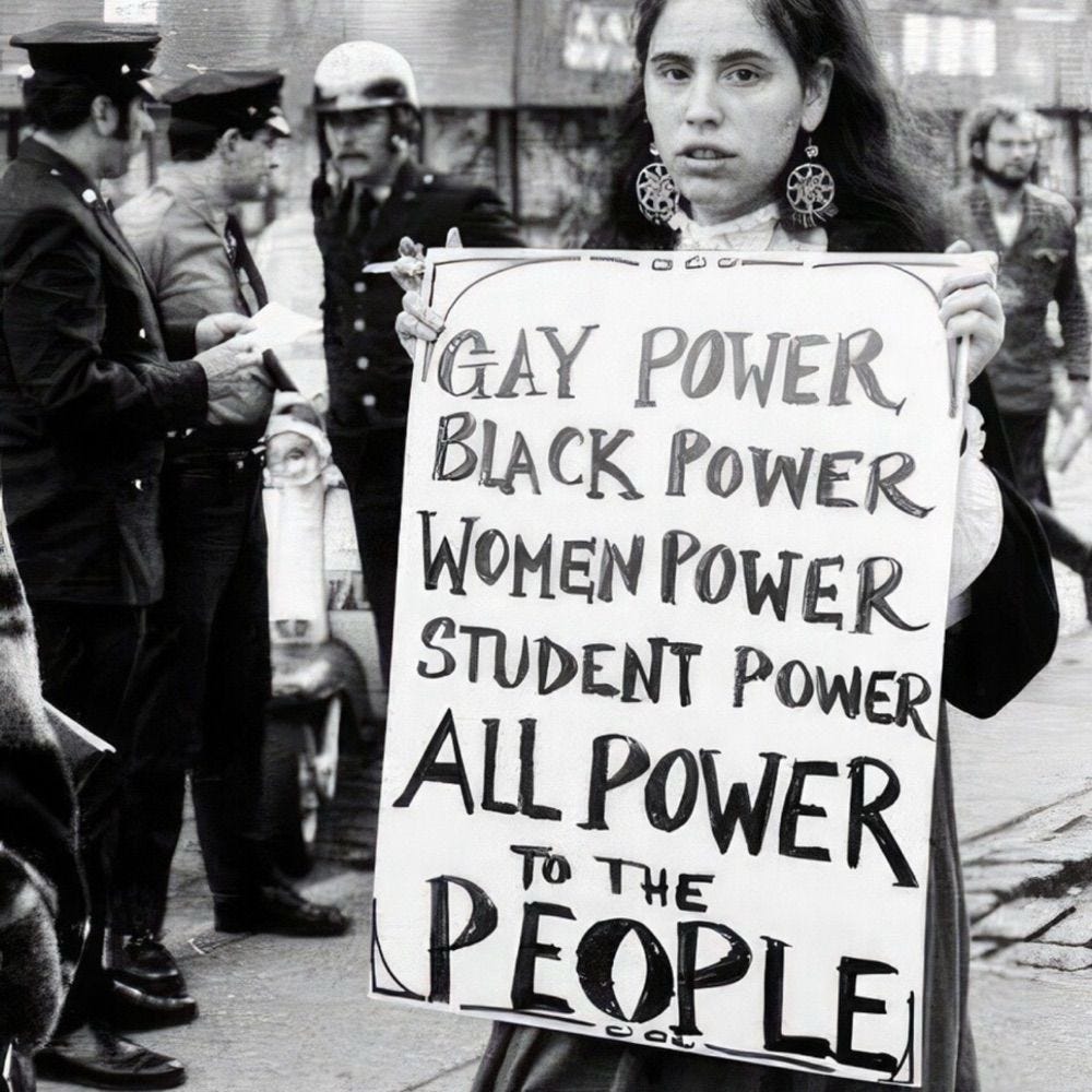 An old photo of a woman holding a sign which reads GAY POWER BLACK POWER WOMEN POWER STUDENT POWER ALL POWER
TO THE
PEOPLE