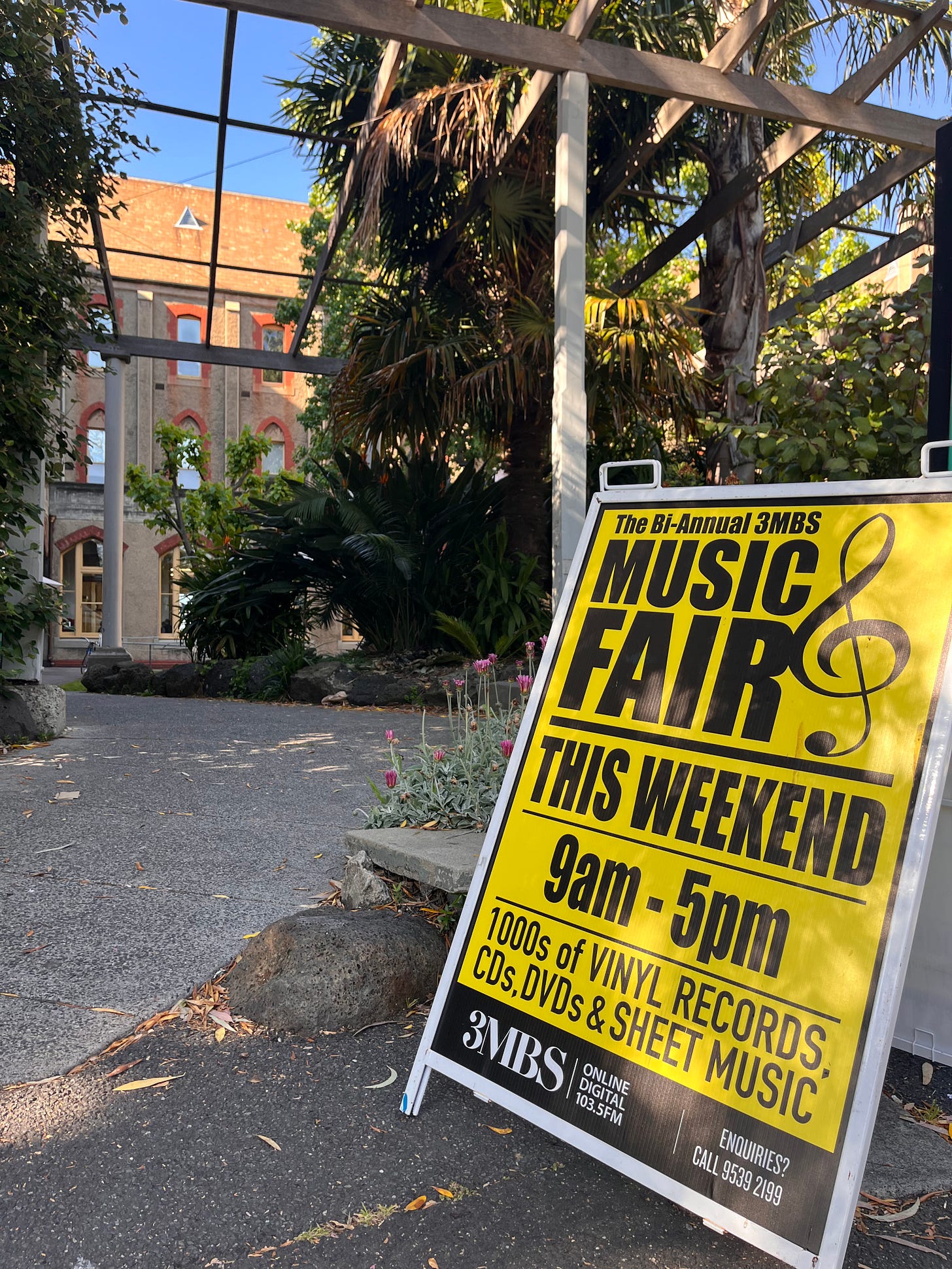 A yellow sign outside Abbotsford Convent reads 'The Bi-Annual 3MBS Music Fair'