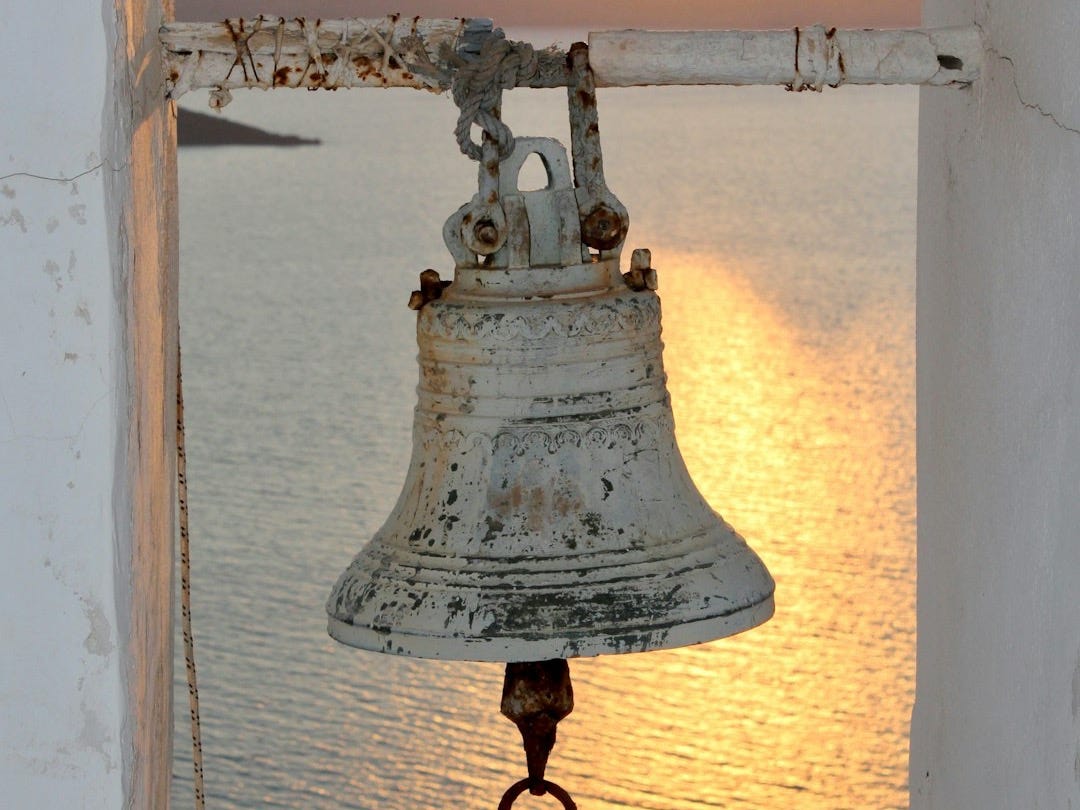white and black metal bell near body of water