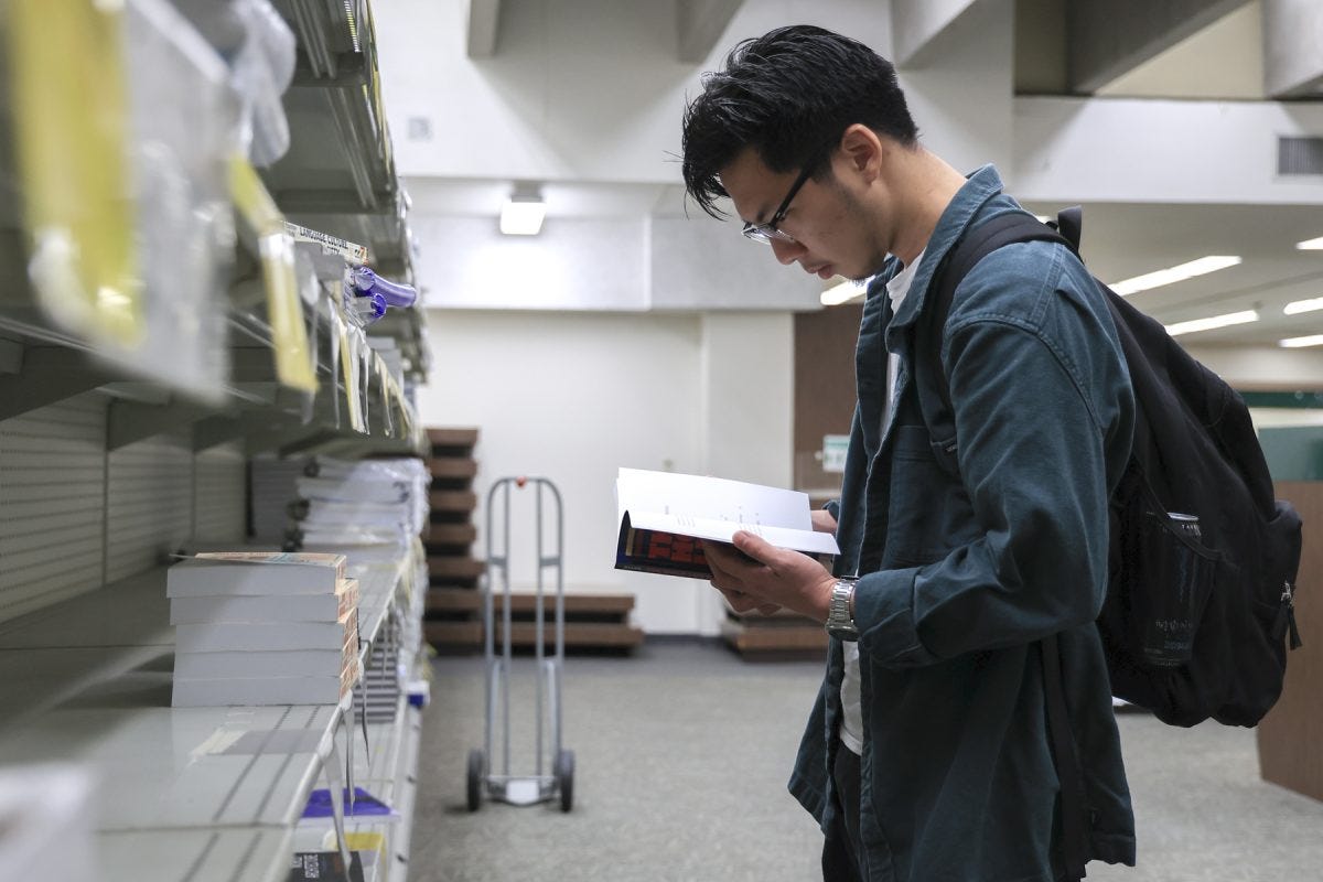 Zion Kim, 22, anthropology major, reads through a textbook in an aisle of the El Camino College Bookstore on Wednesday, April 30. Textbooks will no longer be available for sale in the Bookstore and will be outsourced to online purchasing through an affiliate of Barnes & Noble in fall 2025. Kim said having a Bookstore on campus makes a student feel part of the community. He also said people will lose the experience of flipping through textbook pages at the Bookstore since that can't be done online. (Eddy Cermeno | The Union)