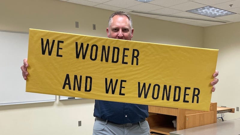 Dr. Dave holding a sign that says, "We wonder and we wonder" Dr. Dave holding a sign that says, "We wonder and we wonder"