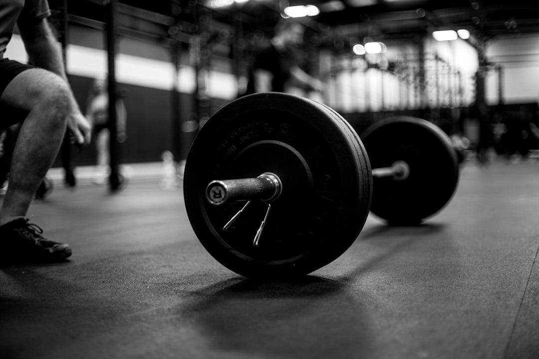 a man squatting down next to a barbell in a gym