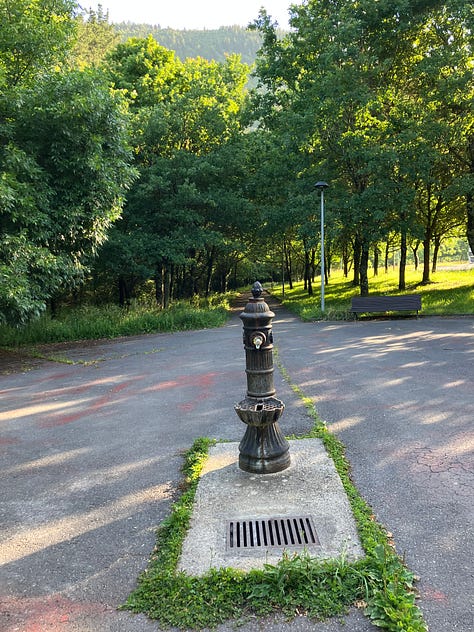 a water fountain in a park setting, two more rocky paths paved with cobblestones