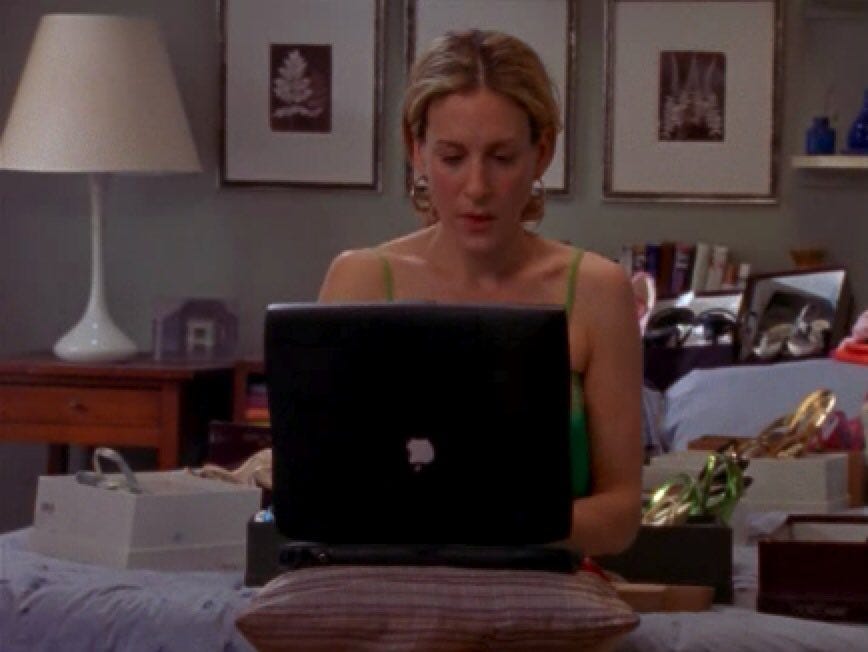 still de Sex and the City en el que Carrie Bradshaw escribe en su laptop desde su cuarto still de Sex and the City en el que Carrie Bradshaw escribe en su laptop desde su cuarto