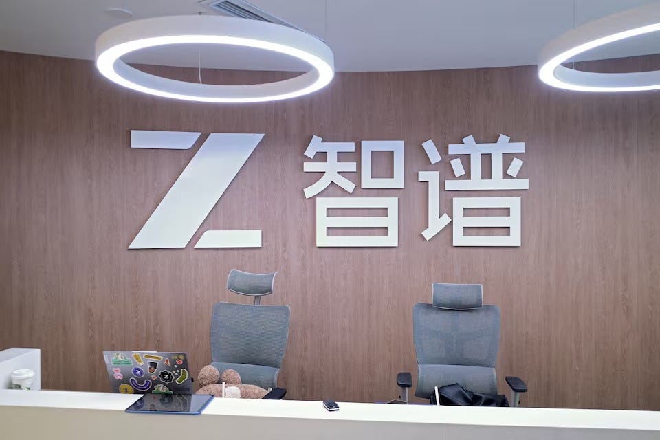 Zhipu AI logo and Chinese characters on a wood-paneled wall above a reception desk with two grey chairs Zhipu AI logo and Chinese characters on a wood-paneled wall above a reception desk with two grey chairs