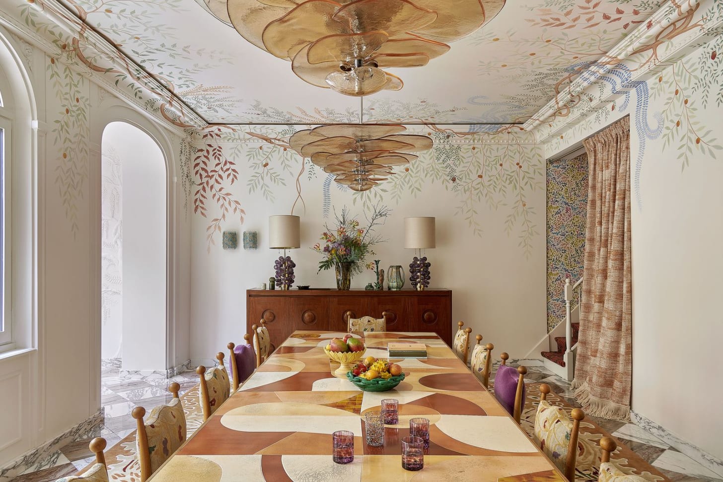 Meeting room featuring long table set with cups bowls of fruit two sculptural amber colored light fixtures hanging from... Meeting room featuring long table set with cups bowls of fruit two sculptural amber colored light fixtures hanging from...