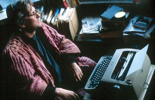 A man staring out of the window while sitting at a typewriter in a dressing gown A man staring out of the window while sitting at a typewriter in a dressing gown