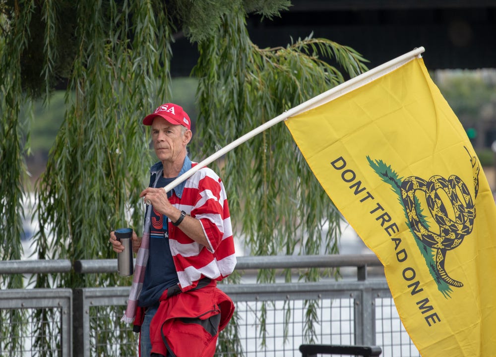 An old man carries a "Don't Tread on Me" flag attached to a PVC pipe after the 30 minute Proud Boys rally got moved to the east side of the Willamette River An old man carries a "Don't Tread on Me" flag attached to a PVC pipe after the 30 minute Proud Boys rally got moved to the east side of the Willamette River