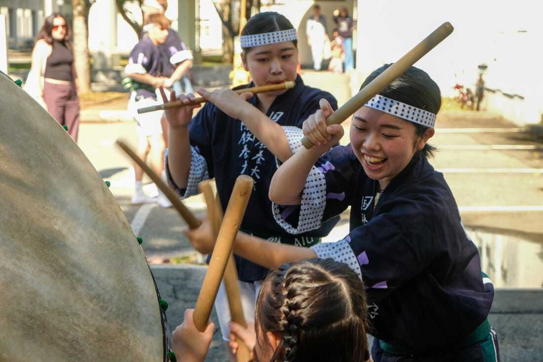 A musician, or “ohayashi,” helps a child try a drum at a Kanto performance in Japan’s Akita prefecture.