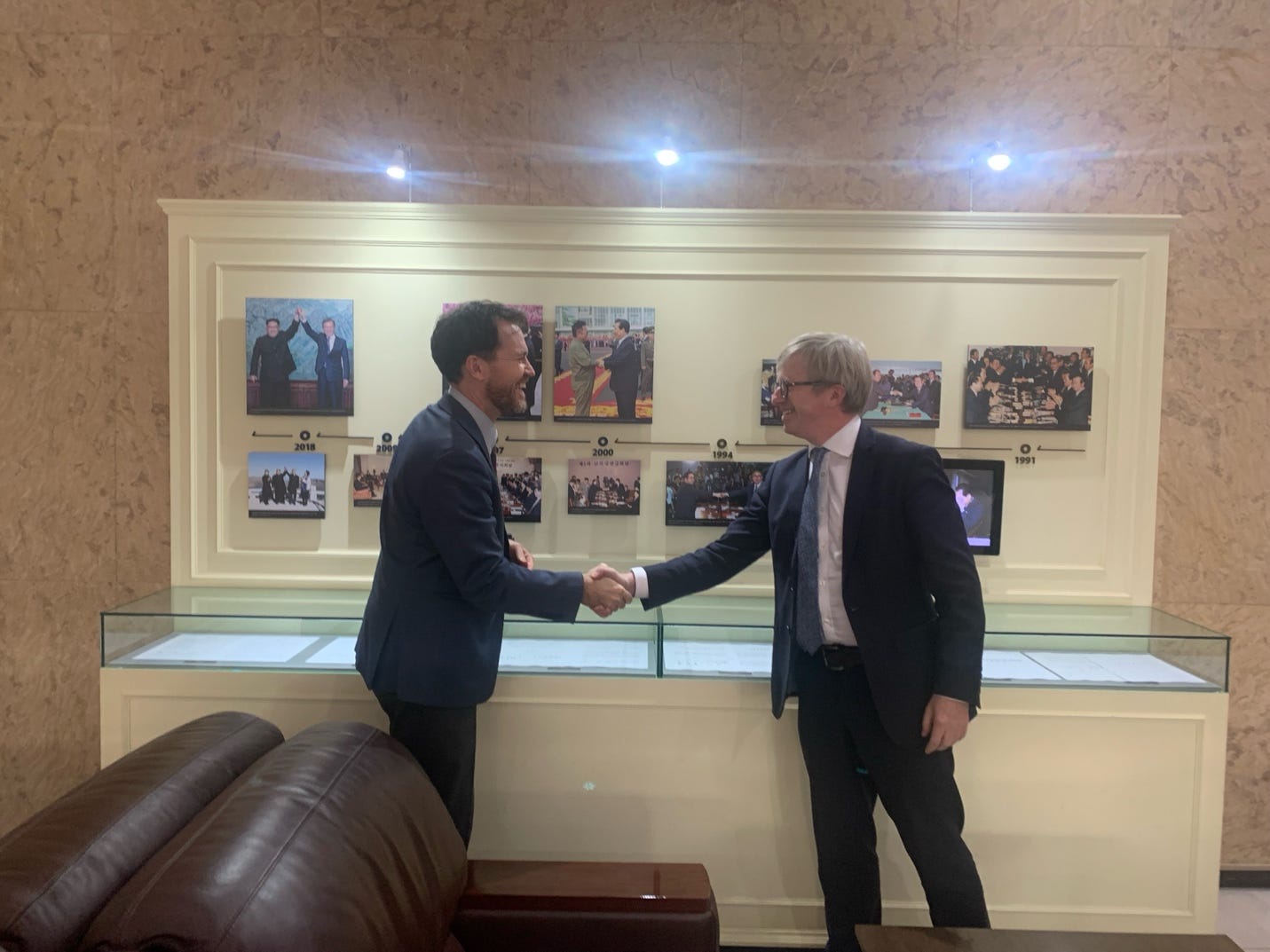 Two men shaking hands in a room

AI-generated content may be incorrect.