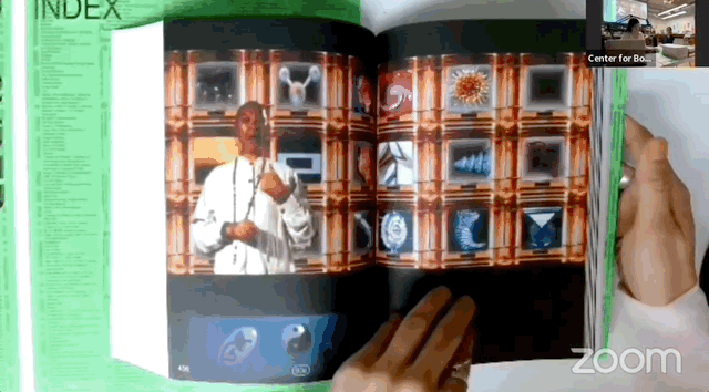 A book on a tabletop. When the page turns, a video of a large body of water and the horizon pops up.