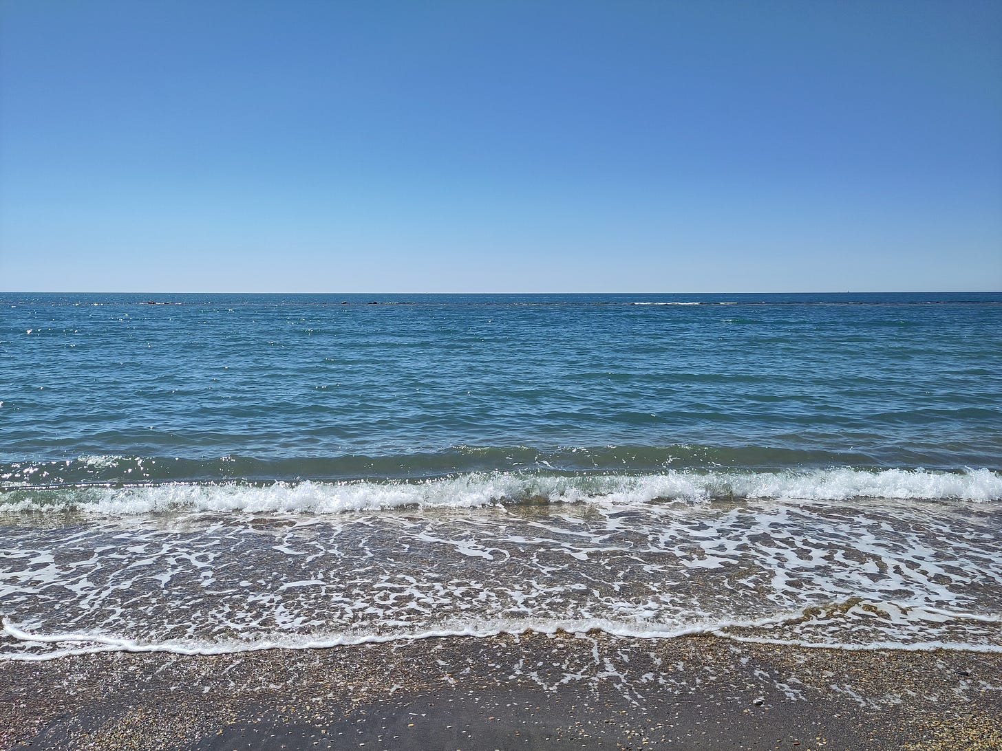 Fotografia di un mare calmo visto dalla riva, con un cielo blu privo di nuvole Fotografia di un mare calmo visto dalla riva, con un cielo blu privo di nuvole