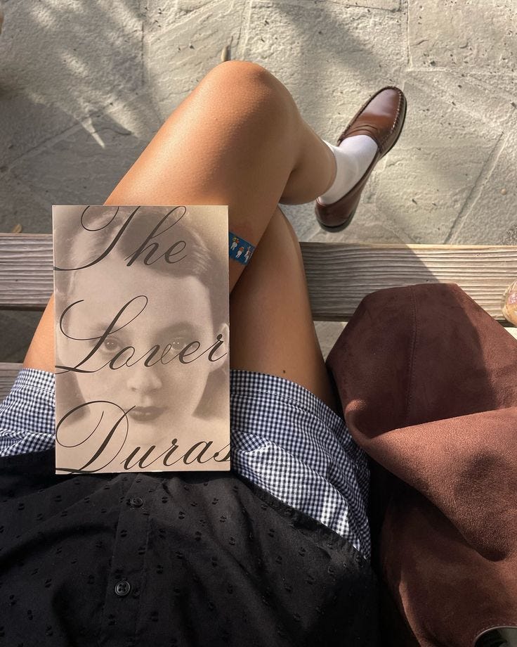 This may contain: a woman laying on top of a wooden bench next to a book titled the love dana