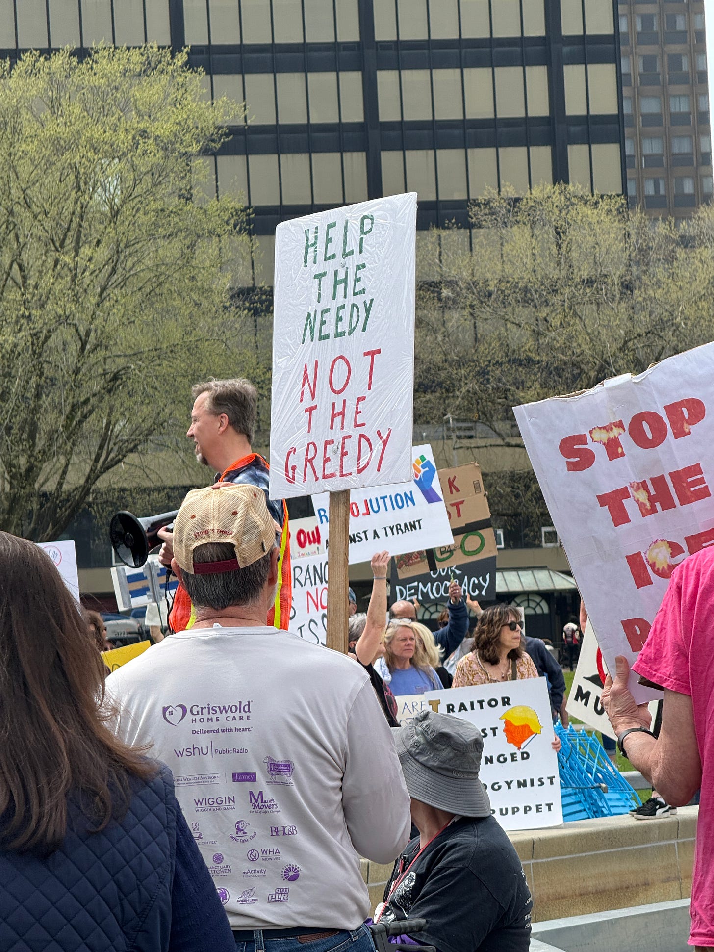 Crowd of protestors - man with sign that says "Help the Needy not the Greedy