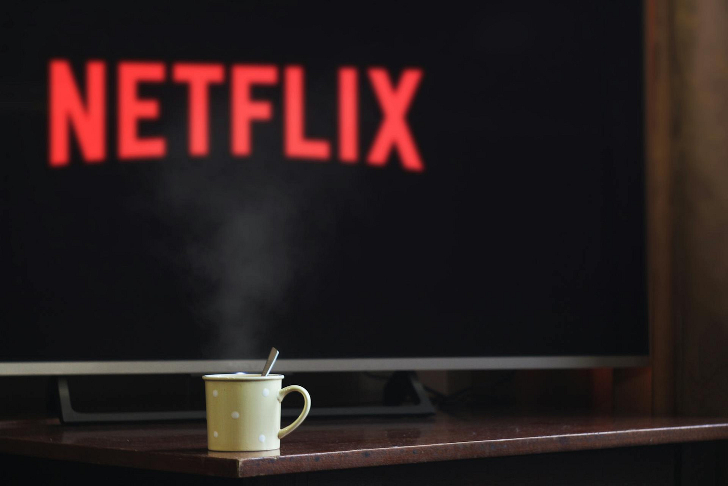 Photo of a TV screen that says "Netflix" and a coffee cup in front of it