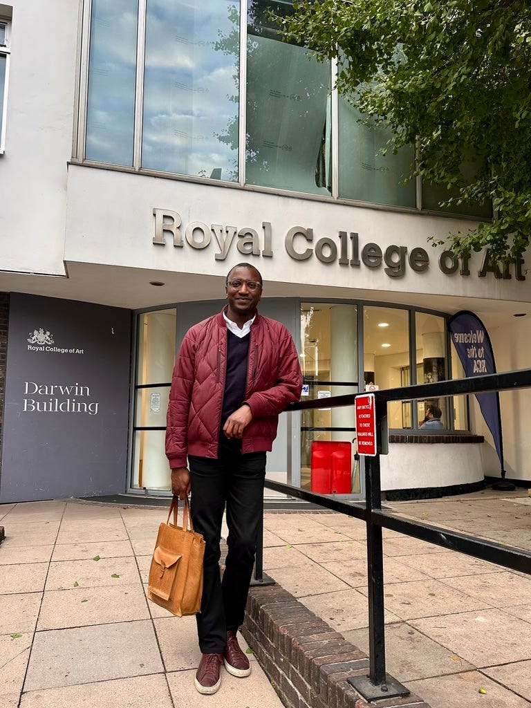 Photo of Michael Kibedi, a tall Black man who is a guest lecturer for the Design Future masters, standing outside the Darwin Building of the Royal College of Art in Kensington. Photo of Michael Kibedi, a tall Black man who is a guest lecturer for the Design Future masters, standing outside the Darwin Building of the Royal College of Art in Kensington.