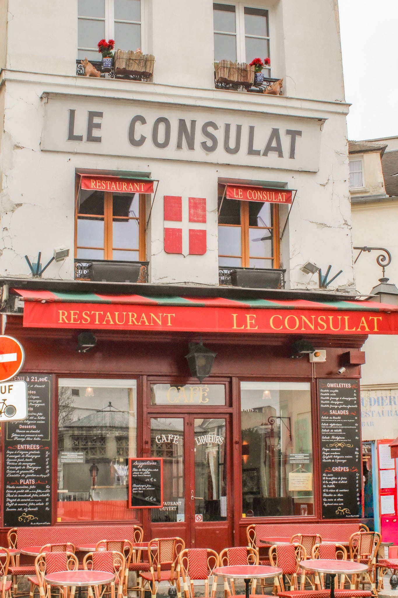 Le Consulat restaurant on Rue Norvins in Montmartre, a traditional Parisian café with its distinctive red awnings and terrace seating.