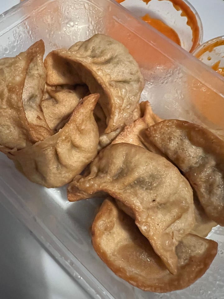 A dish of broken up samosas, topped with sauce, chickpeas, vermicelli, yoghurt & pomegranate seeds plus 3 dishes of different shaped filled dumplings, one with sauce