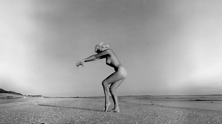 A four-image grid of vintage black-and-white photographs connected to Bunny Yeager: the top-left shows Yeager holding a camera while photographing a nude model lounging on the deck of a boat; the top-right shows a nude woman posing in a dramatic stance on an empty beach; the bottom-left shows a nude woman playfully pulling on a rope at the shoreline; and the bottom-right shows a woman in a bubble bath turning toward the camera with a smile.