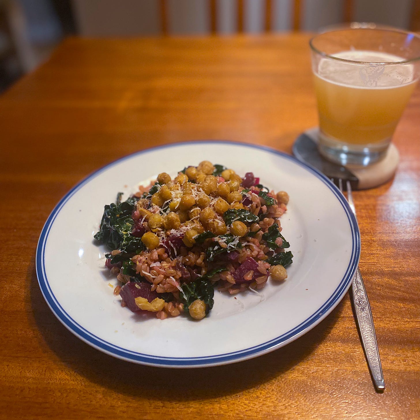A white plate with a blue rim, filled with the salad described above, the chickpeas and some grated pecorino sprinkled over the top. On a coaster in the background is a glass of hazy IPA.