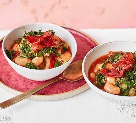 Prosciutto, kale & butter bean stew served in bowls Prosciutto, kale & butter bean stew served in bowls