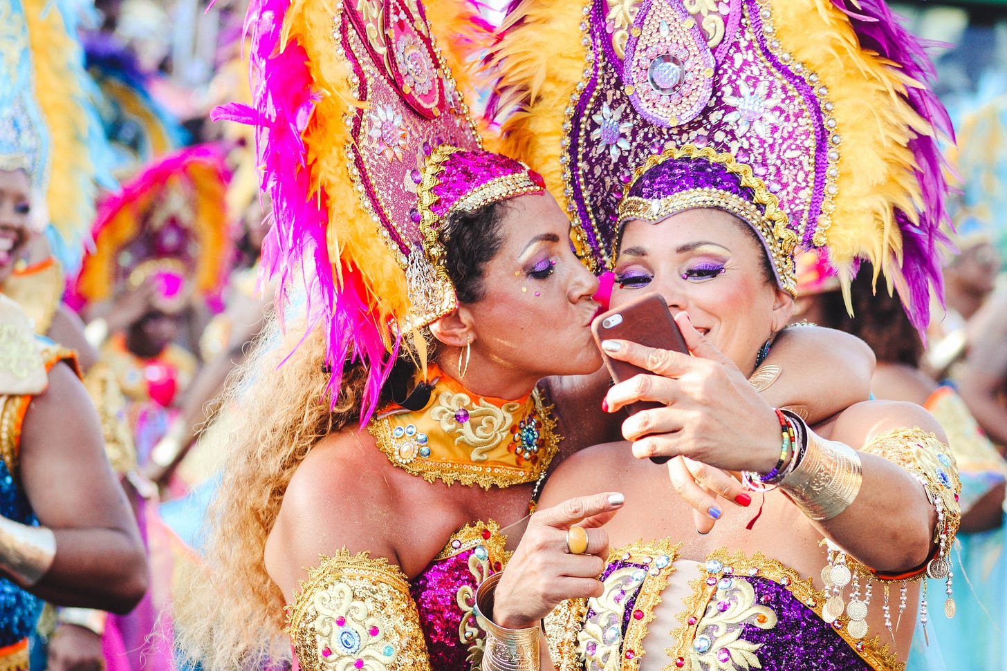 Two women Carnival dancers pose for a selfie as one kisses other on the cheek Two women Carnival dancers pose for a selfie as one kisses other on the cheek