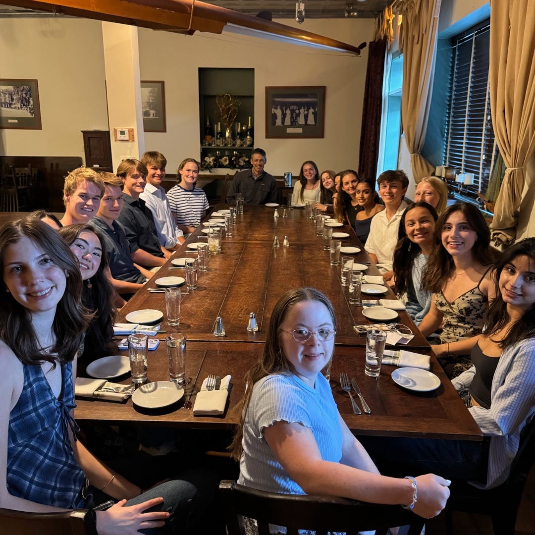 group of teens and family seated around a long wooden table
