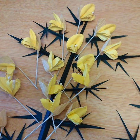 Image 1 is a cup full of mauve flowers, image 2 a collection of yellow pea- style flowers and deep green spikes, Image 3 is a series of cutout green stems with thorns with some dark green leaves and pink flowers. All are made of paper and depict works in progress