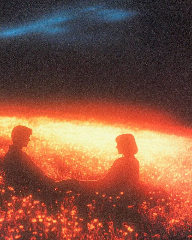 This may contain: two people are sitting in the grass at night with bright lights shining down on them This may contain: two people are sitting in the grass at night with bright lights shining down on them