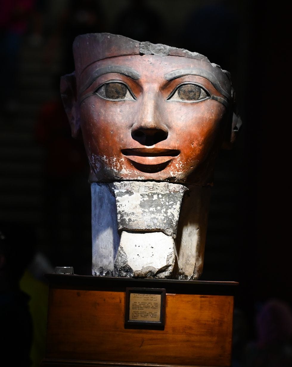 colored limestone head statue of a woman rests on a podium