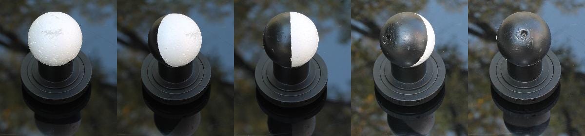 A styrofoam ball, painted half black and viewed from different angles, illustrates the phases of the moon.