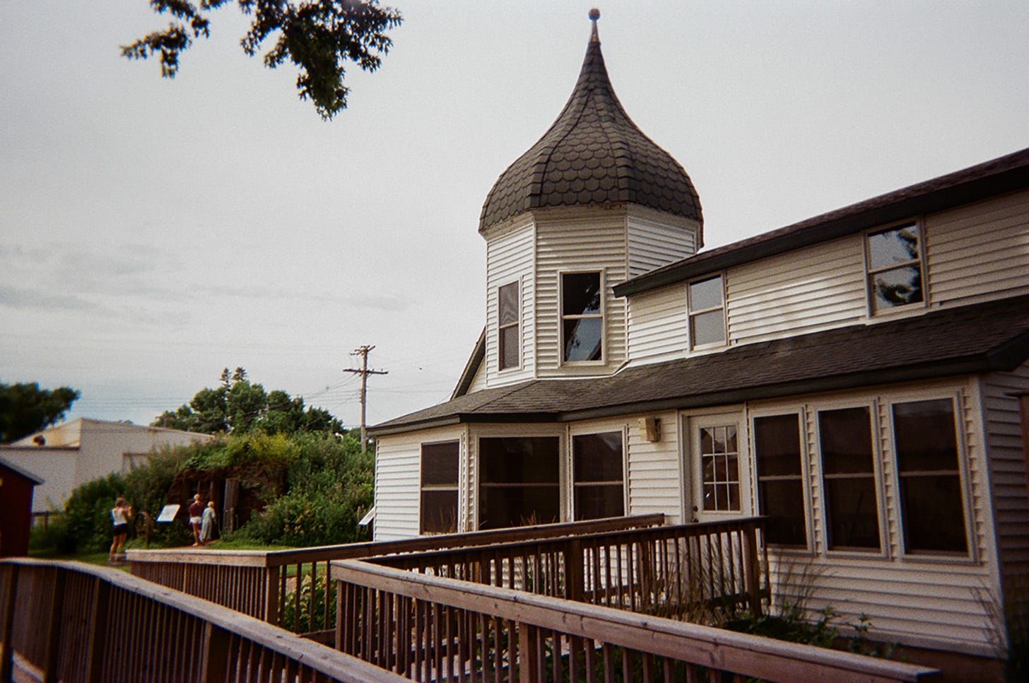 A white, two-story house with black shingles and onion dome built in 1890.