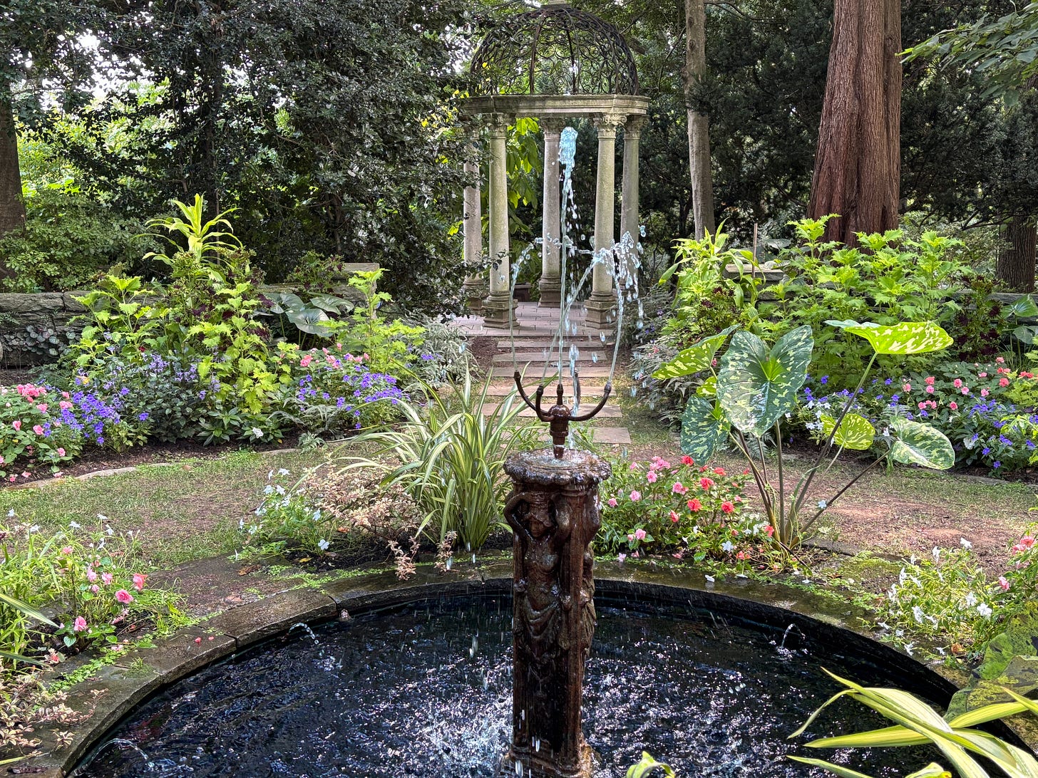 a green garden with a small fountain