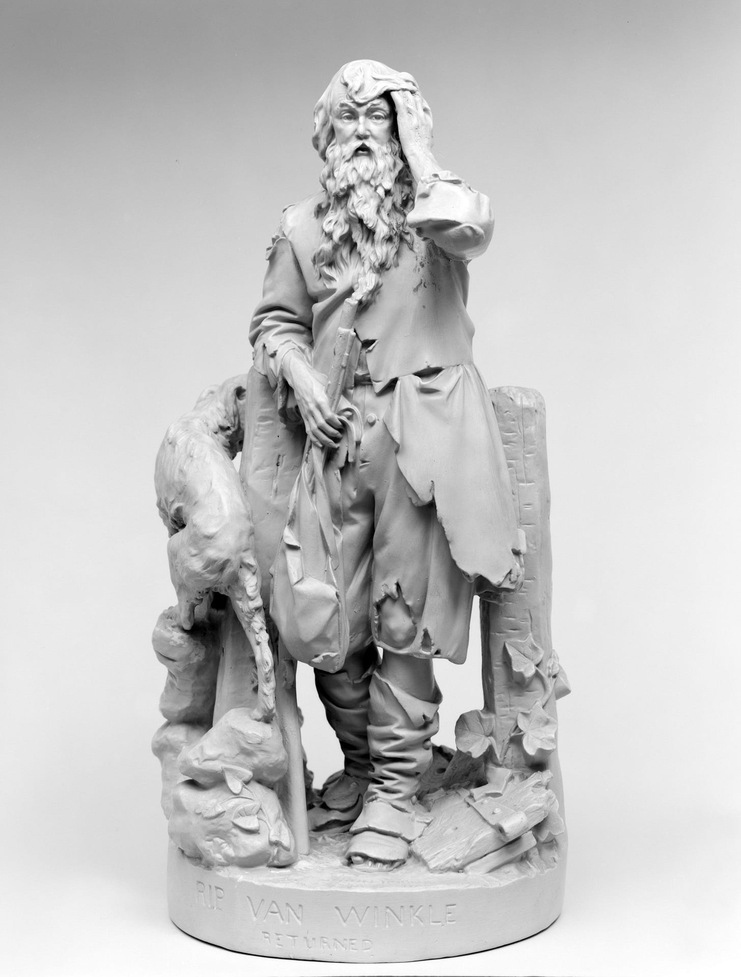 Small painted plaster sculpture of Rip Van Winkle returning after his 100 year sleep. The sculpture is painted white and the figure is in tattered clothes from head to toe. He wears a cap, has a long, luscious beard, and a dog by his side.