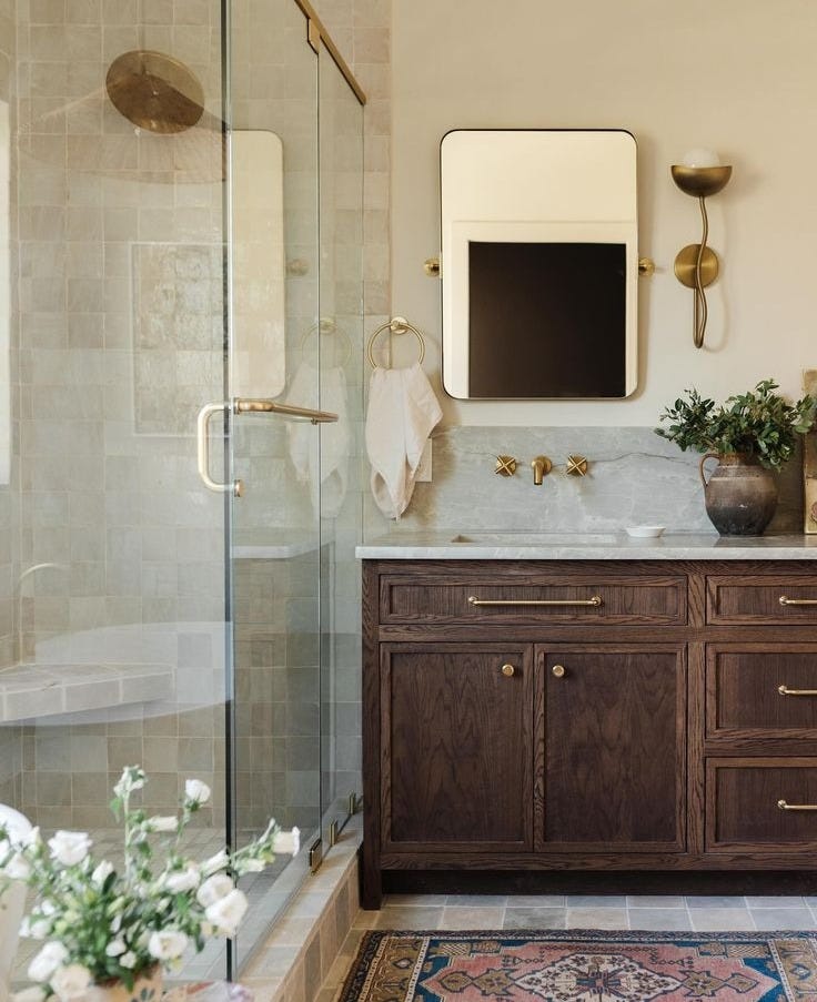 This may contain: a bathroom with a sink, mirror and bathtub next to a flower vase on the floor