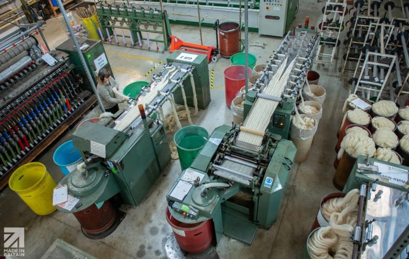 Aerial view of The Natural Fibre Company mill in Cornwall who scour, card and spin wool. Colourful tubs are placed about, some full of wool rovings. Machines look well used and are in use in the photo.