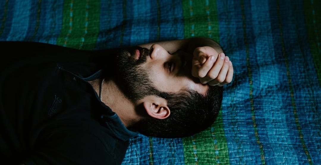 man in black shirt lying on green textile