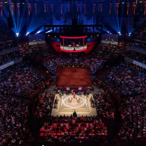Getty Images A view of the Royal Albert Hall, showing the crowds surrounding the ring, which has two sumos fighting in it, with the judge looking over them. Above that is the temple roof, which has tassles hanging down, and above that is the circular LED screen which has the match playing on it Getty Images A view of the Royal Albert Hall, showing the crowds surrounding the ring, which has two sumos fighting in it, with the judge looking over them. Above that is the temple roof, which has tassles hanging down, and above that is the circular LED screen which has the match playing on it